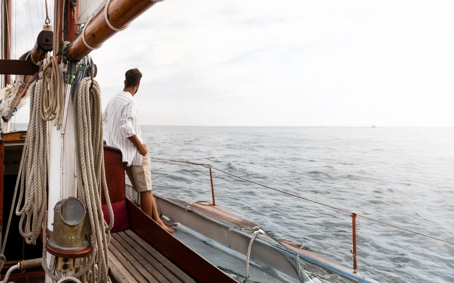 Spokojny nastrój rejsu: mężczyzna na pokładzie jachtu patrzy na morze w Grecji - Sailing To Go - czarter jachtów i katamaranów w Grecji
