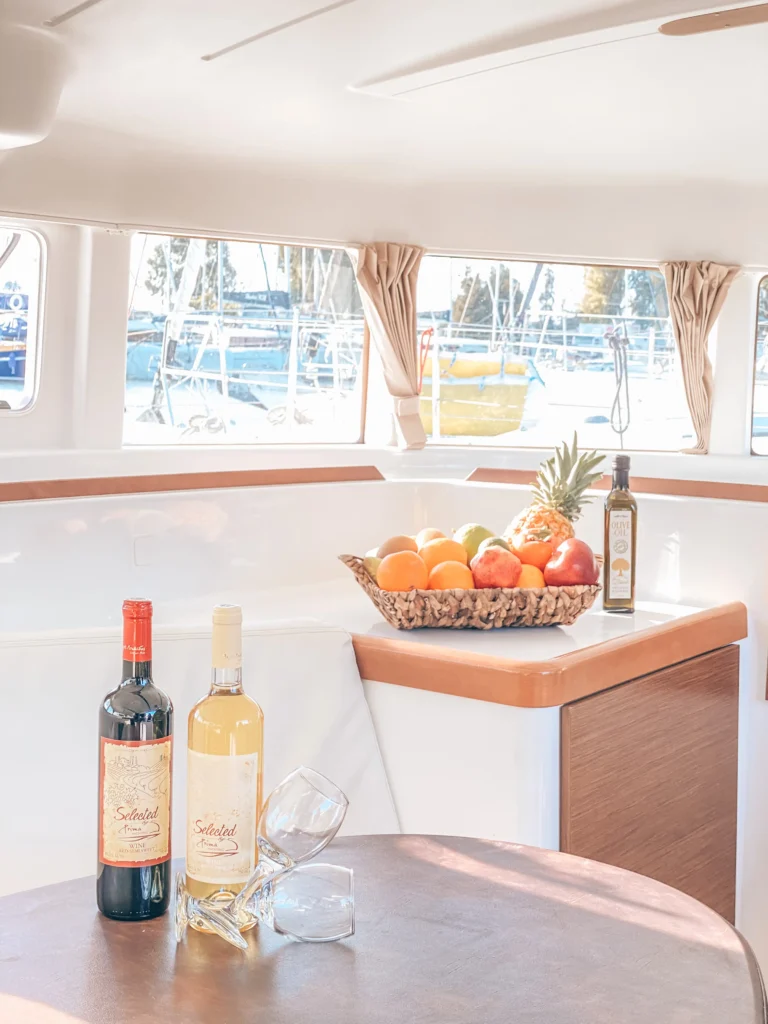Lagoon 380 Tiny K interior saloon table details with fruit and wine, charter in Greece