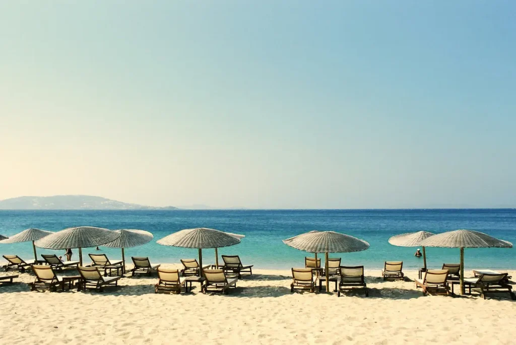 Piaszczysta plaża na Santorini z białymi parasolami i leżakami nad lazurowym morzem