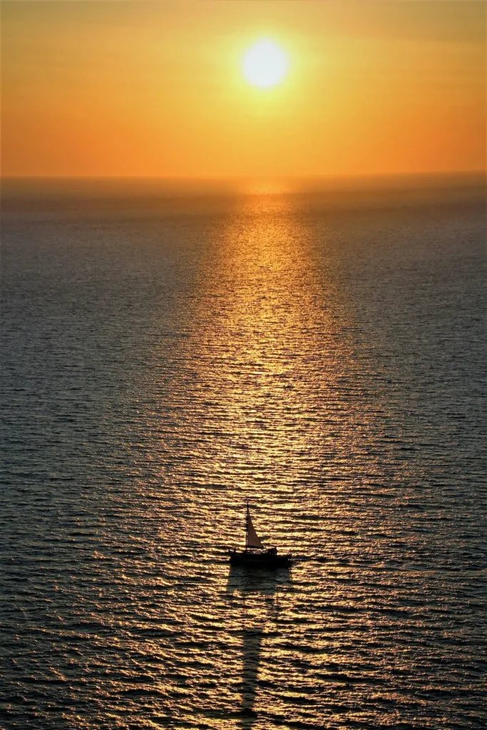 Jacht żaglowy o zachodzie słońca na Morzu Egejskim w pobliżu Santorini