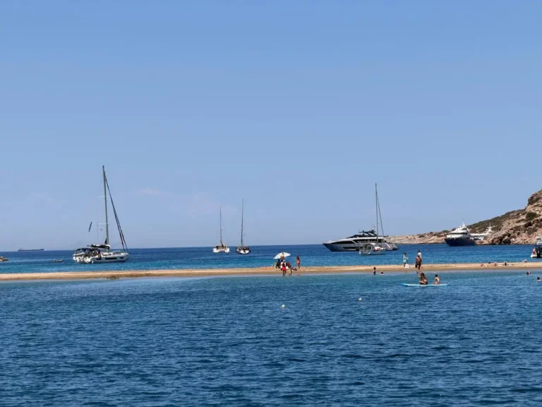 Plaża Kolona na wyspie Kythnos z charakterystyczną piaszczystą mierzeją oraz jachtami i katamaranami stojącymi na kotwicy.