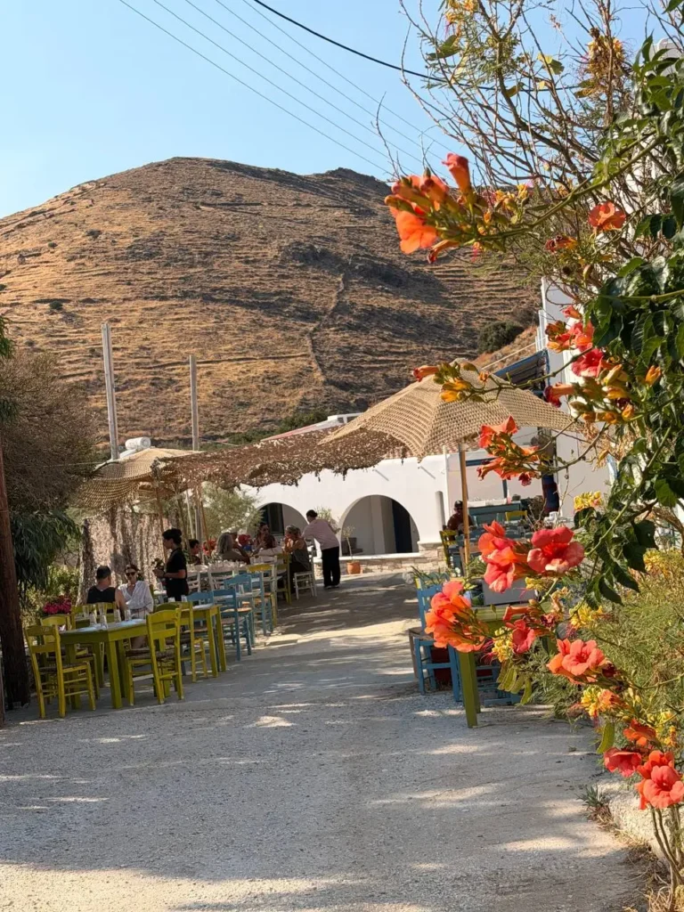 Tradycyjny plac z greckimi tawernami i kwitnącymi kwiatami na wyspie Kythnos.